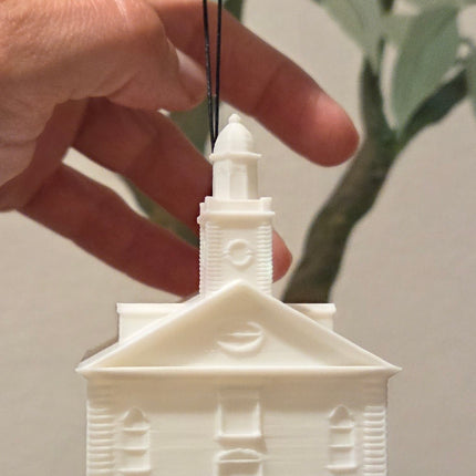 Hand holding a small white architectural model of a building against a neutral background