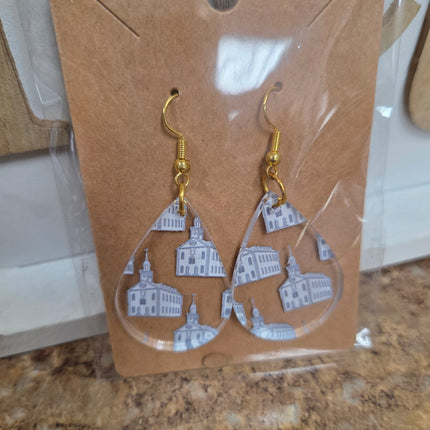 Earrings with cityscape design on a cardboard backing, on a marble surface.
