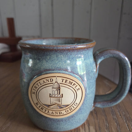Blue ceramic mug with a logo on a wooden surface